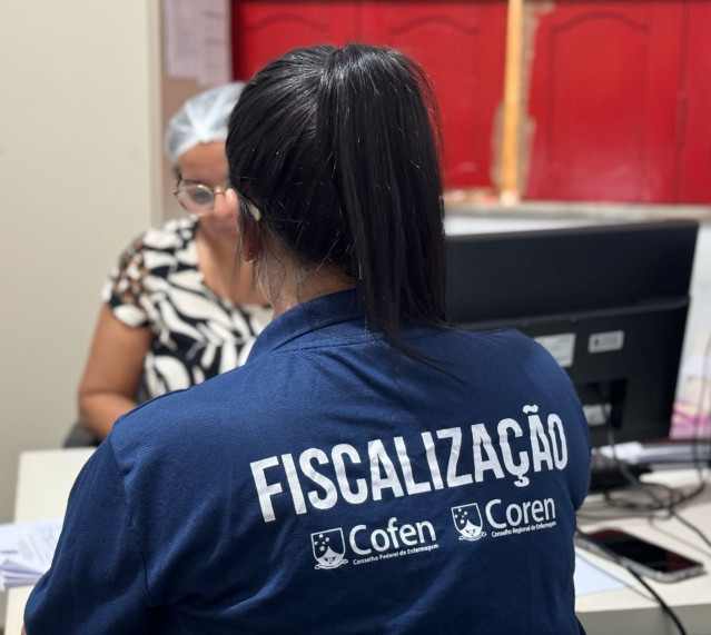Uma enfermeira fiscal do Coren-PA, vestindo um jaleco azul escuro com 